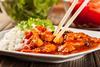 picture of sweet and sour chicken on a plate with rice and chopsticks