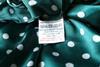 A close up photo of a care label in a green shirt saying 100% polyester