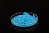 A photograph of blue copper(II) sulfate powder in a glass Petri dish against a black background