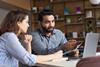 Professional education mentor discussing with mentee in office with laptop on desk