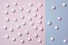 A photo of white balls on a blue and pink background. There are more balls on the pink background than the blue.
