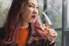 A woman pulling a face of disgust as she smells a glass of wine