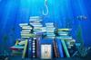 Fishing hook above pile of books underwater with clownfish to the right side