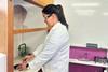 Orla Casby working as a science teacher wearing a lab coat and safety glasses working at a fume hood