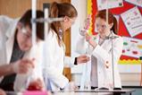 Students in a school lab using a burette filler to measure liquid for a titration