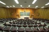 An image showing an empty auditorium or lecture theatre, shot from the back at the top looking down to the lecturer's position