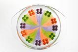 A glass dish with sweets around the edge whose colours have bled into the middle