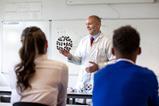A chemistry teacher showing a high school class a model of buckminster fullerene