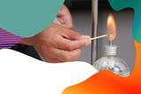 A hand is lighting a spirit burner with a match and there is a colourful border around the edge of the image