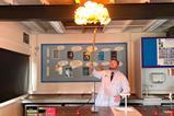 A science teacher using a long splint to light some hydrogen bubbles in a large fireball