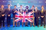 Four high school students in suits and ties with medals and a union jack flag