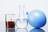 A brown powder in a glass beaker, a clear liquid in a carafe and a gas in a blue balloon.