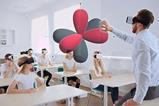 A teacher and students all wearing VR headsets examine an electron shell orbital diagram in 3d