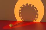 A spotlight on a small covid virus casting a large silhouette on a wall