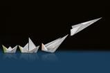 A 3d illustration of some origami made from structure strips. The origami develops from a simple boat through other more complex boats to a sleek paper airplane which is taking off.