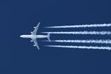 A passenger jet plane flying overhead leaving trails of vapour