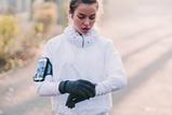 A photo of a woman looking at her smartwatch during a run outdoors