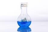 A round glass flask holding blue liquid and a teabag