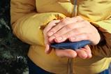 A woman wearing a warm coat outside and holding a chemical hand warmer