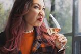 A woman pulling a face of disgust as she smells a glass of wine