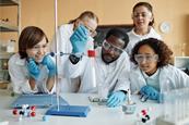 Students in a lab watching a teacher demonstrating a practical