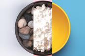 A bowl containing pebbles, another with powdered sugar and an empty bowl