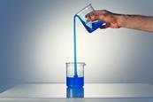 A glass beaker pouring liquid uphill into another