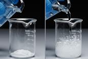 A series of photos showing a latex gloved hand pouring a colourless liquid onto a white powder, leading to a vigorous reaction of bubbles