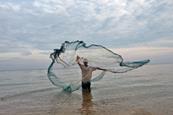 A fisherman in Baucau, East Timor, casts a net in the water to catch small fish