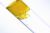 A yellow oil sits on top of a clear liquid in a test tube