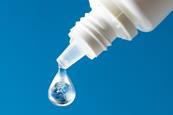 A dropper bottle with a drop of liquid that contains a globe