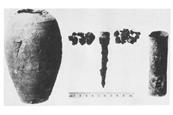 An old black and white photo of a cracked clay jar and some metal components
