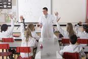 students in a chemistry lab with their hands up to answer a question asked by a teacher