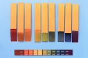 Universal indicator paper strips showing a full rainbow of colours and a comparison strip showing the corresponding pH