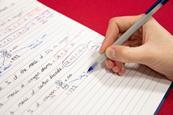 A hand writing chemistry equations with a ball point pen