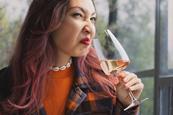 A woman pulling a face of disgust as she smells a glass of wine