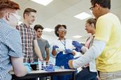 Students and teacher gather around a chemistry classroom laboratory bench