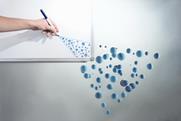 A photo of a hand drawing circles on a whiteboard that turn into blue spheres