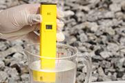 A yellow conductivity meter submerged in a measuring jug of clear liquid