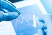 An image showing flexible glass help by two blue gloved hands