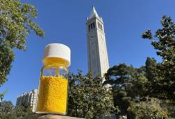 A bright yellow powder in a closed glass jar in front of a university clock tower