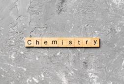 A photograph of wooden tiles with letters spelling the word 'chemistry'