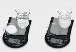 A before and after photo showing that the mass (85.5g) of a beaker of water and a watchglass of salt does not change when the salt has been dissolved in the water