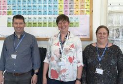 Three people standing in front of a periodic table