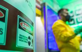 Man in yellow Hazmat clothing with gas mask in lab with dangerous chemicals