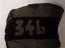 A piece of slate with the number 346 revealed after applying water