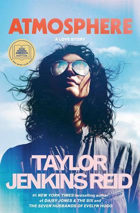 The book cover for Atmosphere A Love Story by Taylor Jenkins Reid featuring a photo of a woman's head and shoulders. She is white with wind swept dark curly hair and she is wearing a jumpsuit and aviator sunglasses reflecting a spaceshuttle launch