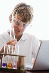 A student with a laptop holding a test tube