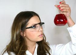 A chemistry student looking at a beaker of red liquid