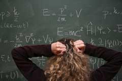 A student trying to work out a math problem on a blackboard and showing frustration